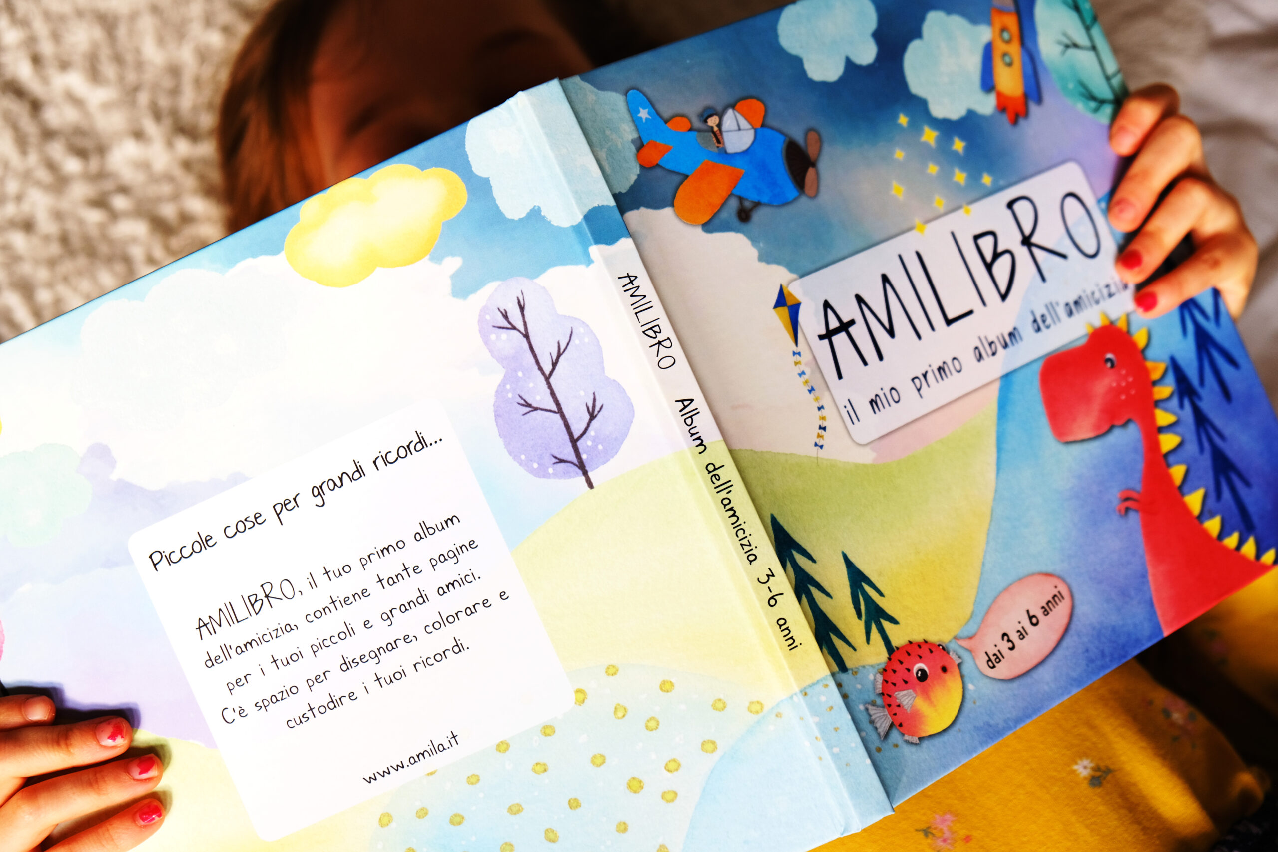 Bambina che mostra la copertina di Amilibro aperto